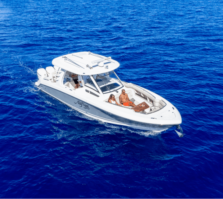 White motorboat with people on board cruising through blue ocean water.