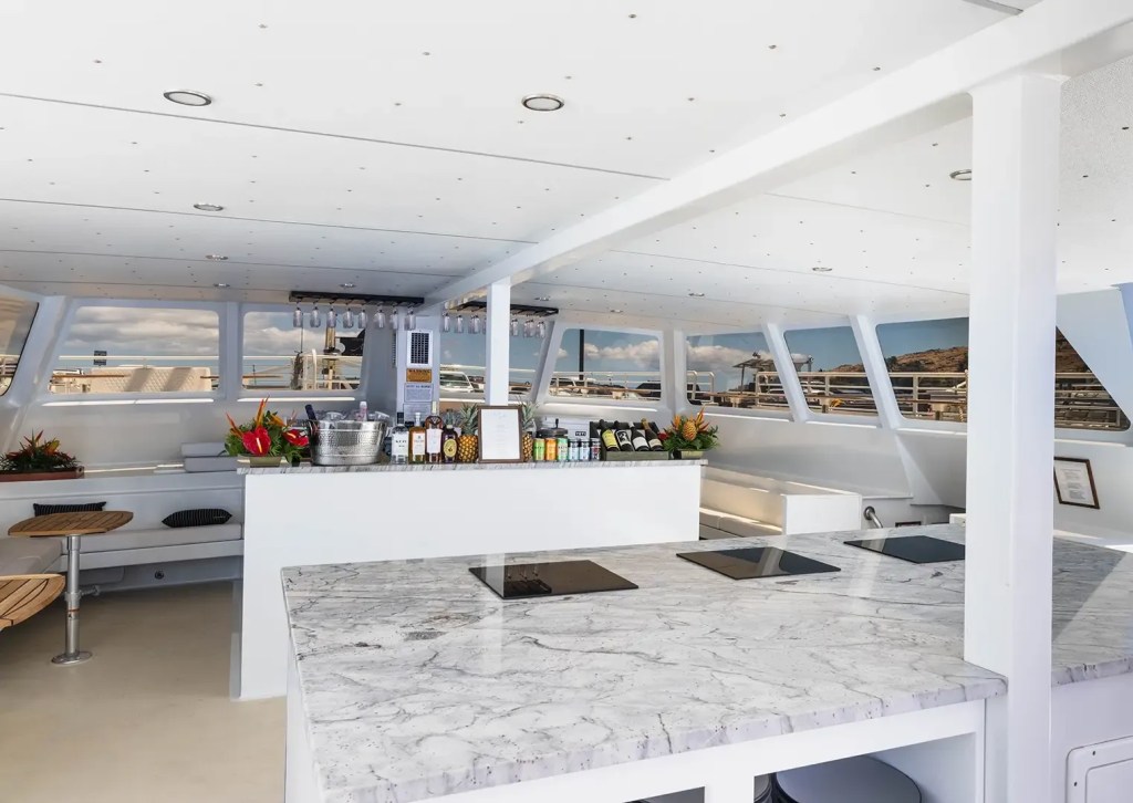 Modern yacht interior with marble countertops, bar area, and large windows overlooking the sea.