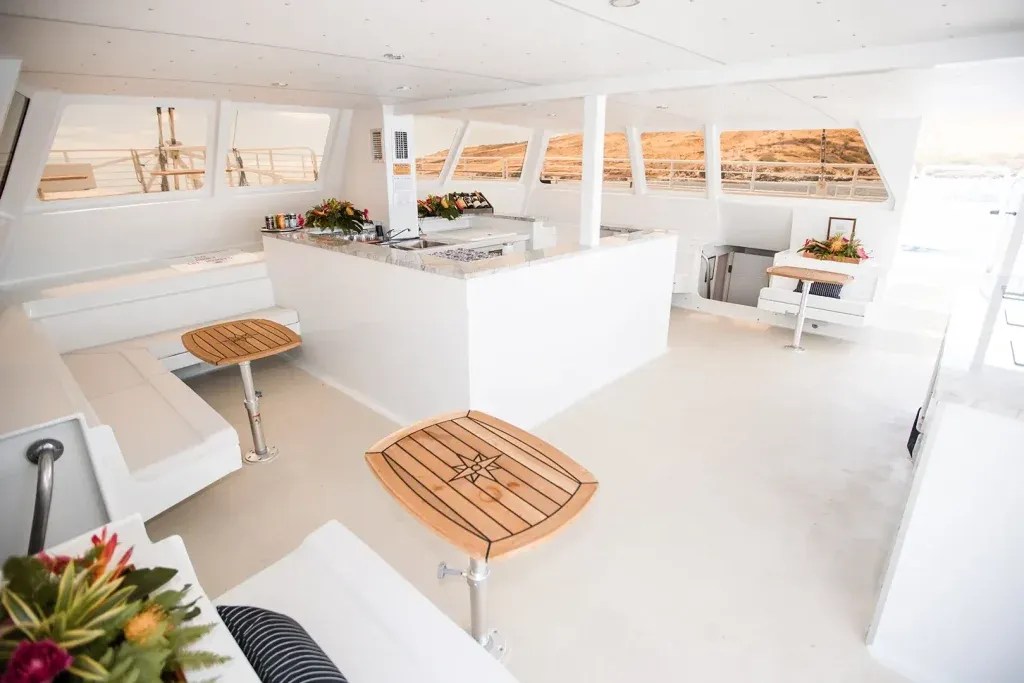 Spacious white boat interior with seating, tables, and floral decorations.