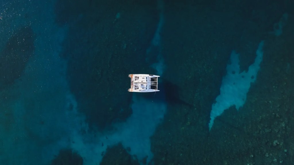 Aerial view of a white boat floating on dark blue water.