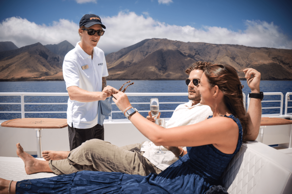 People relaxing on a yacht with a scenic mountain view in the background.