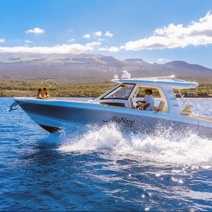 Motorboat with people on blue water, mountainous background under a clear sky.