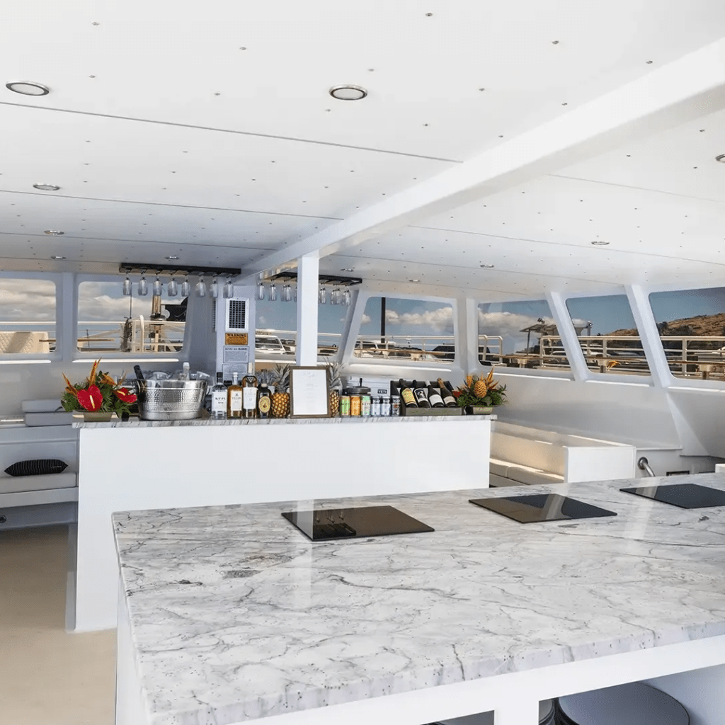 Luxury yacht interior with a marble bar, bottles, and windows overlooking the sea.