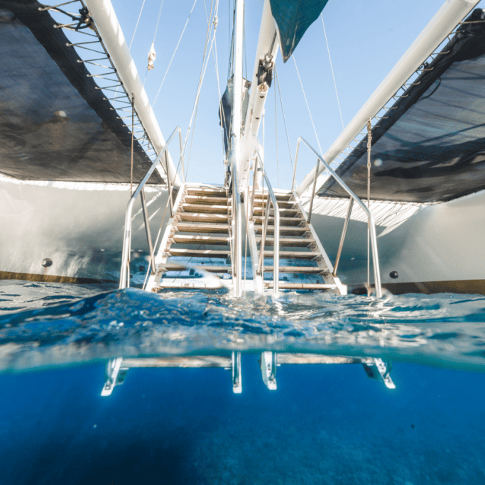 Underwater view of catamaran steps leading into clear blue ocean.